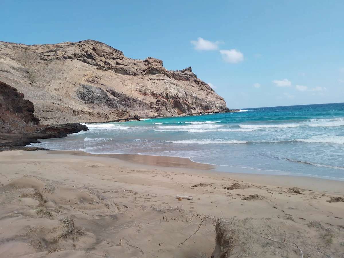 Anahoa beach: pale sand and turquoise water at the foot of a rocky hill