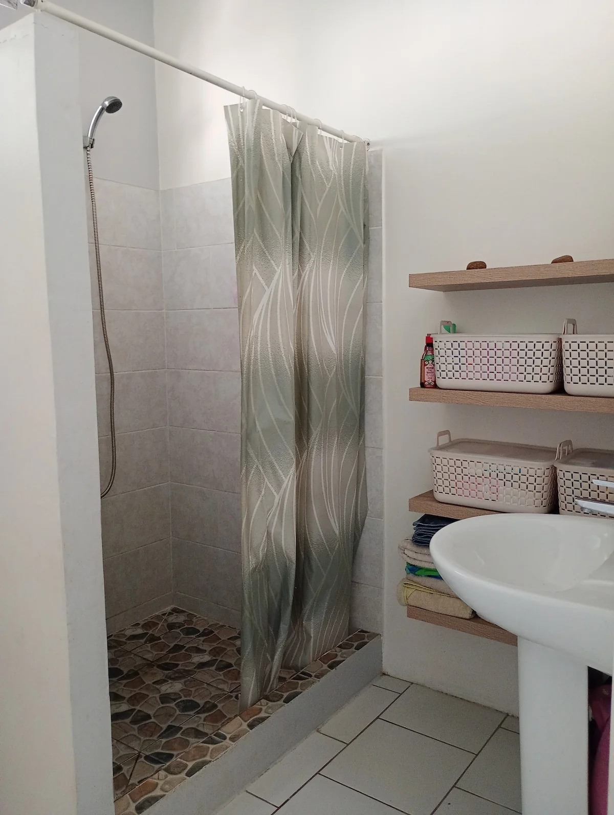 Shower room with a pebble-floored shower, a washbasin and shelves
