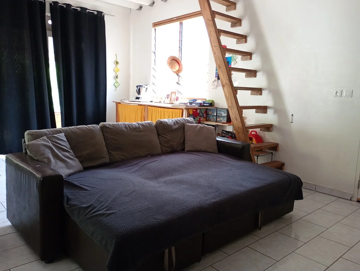 Sitting area with a large dark sofa and a wooden staircase