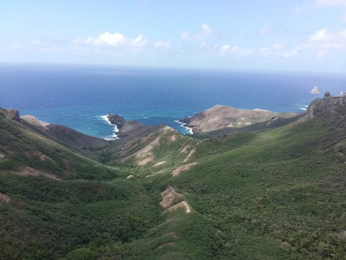 Lush valley running down to the ocean between two rocky headlands